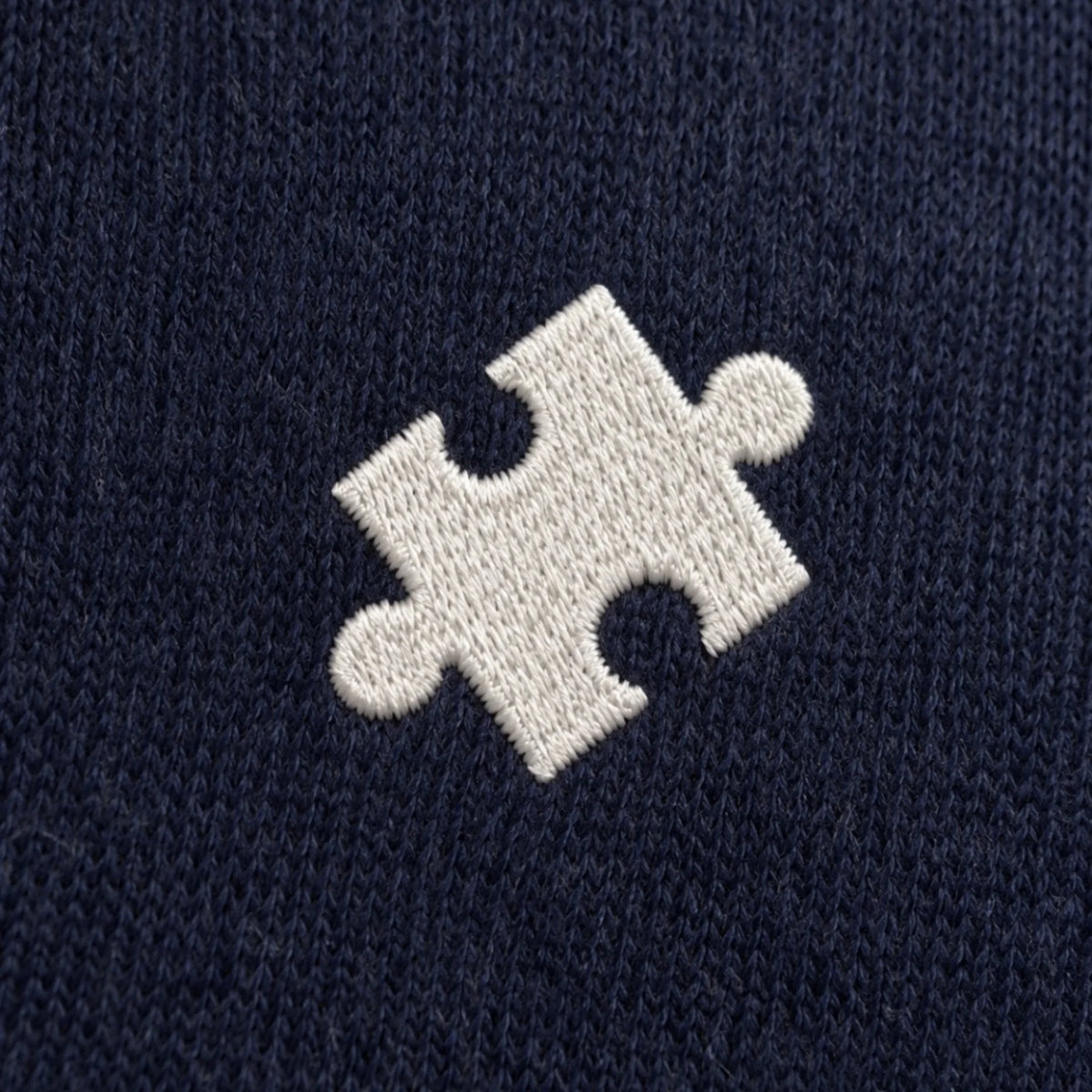Detail des gestickten Puzzlestücks auf dem Herren-Pullover